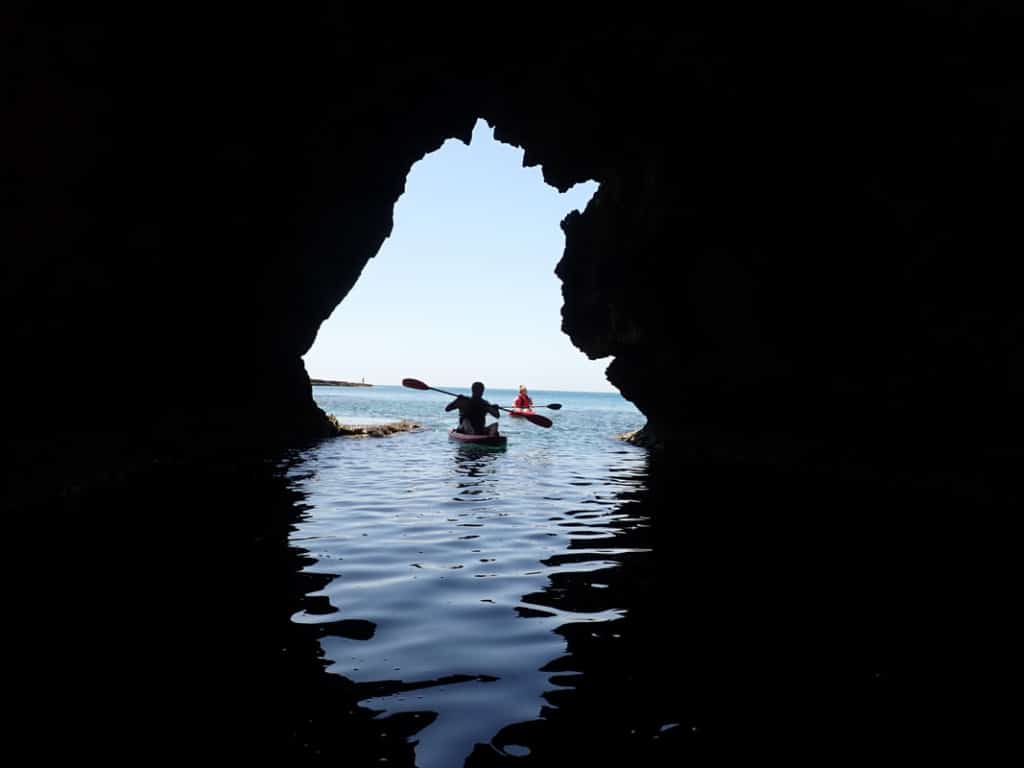 someone canoeing out of a cave through a hole