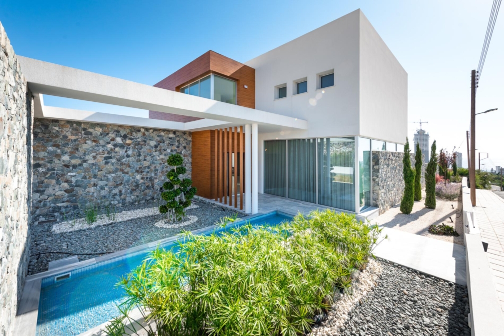 A villa, with a glass door along the side and some plants in the front.