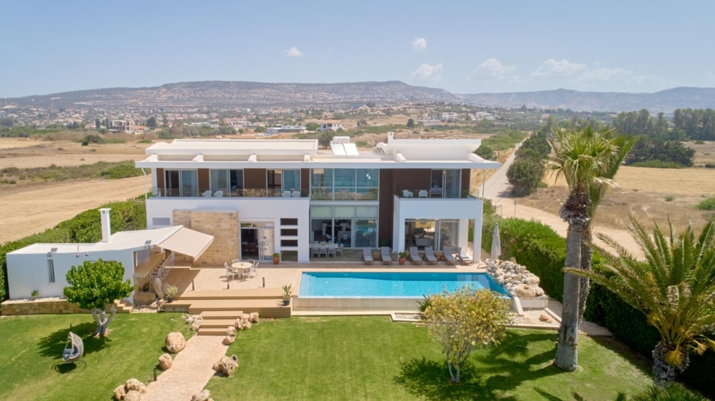 high angle of villa with pool and palm tree in the front, mountains are in the background,